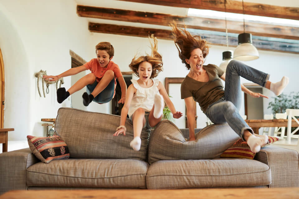 Mother and children jumping onto couch